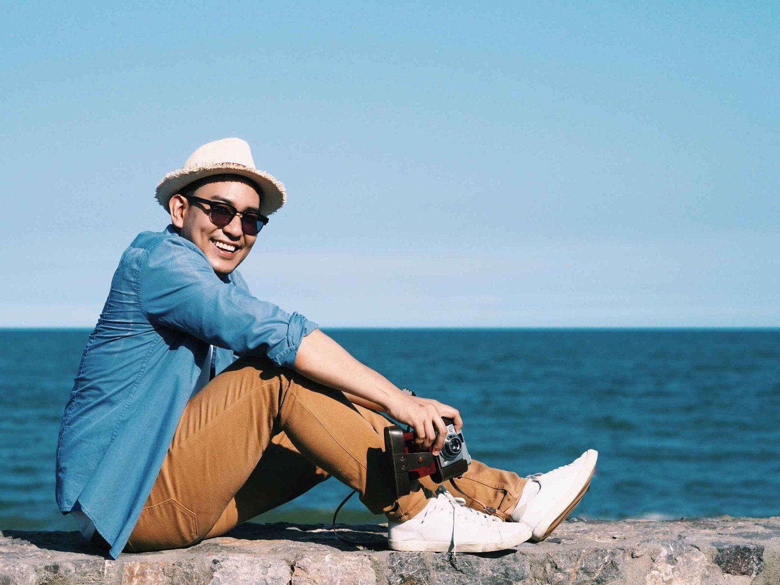 happy-young-traveler-man-sitting-beach-min